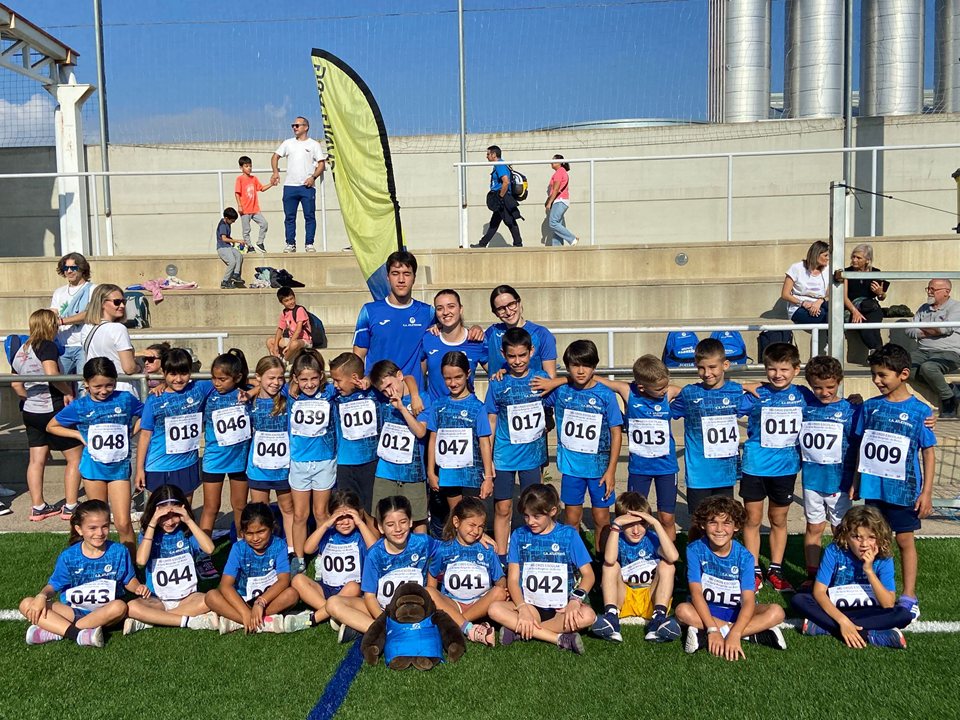 Grup nombrós de joves i adults sobre la gespa davant del graderiu.