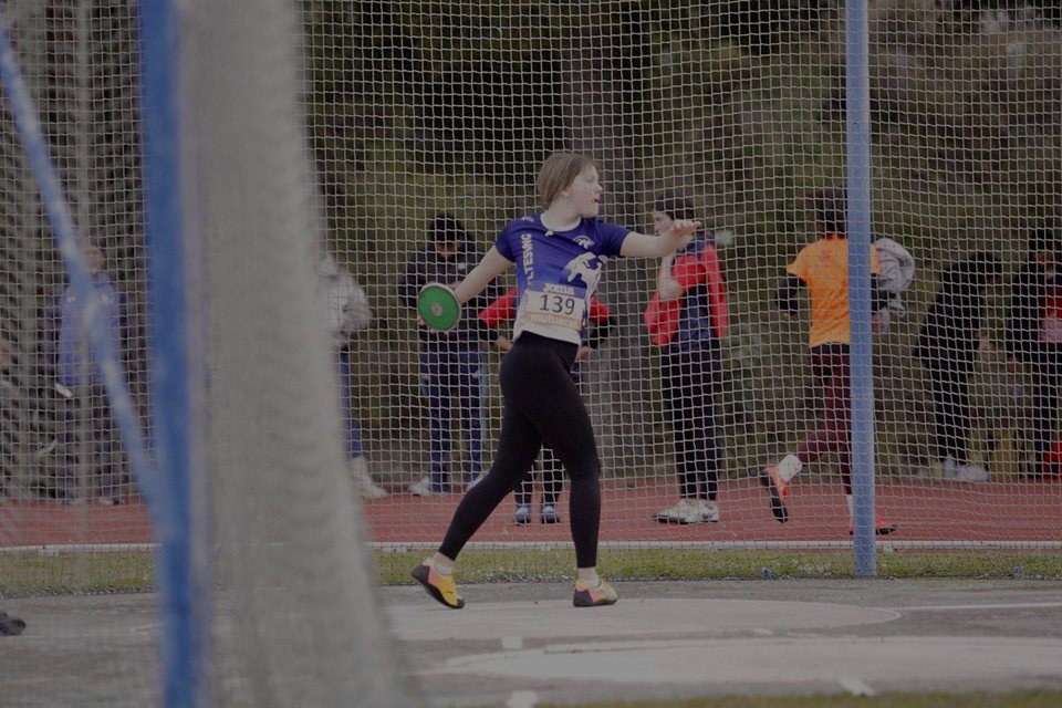 Atleta amb un disc dins d’una gàbia de llançaments.