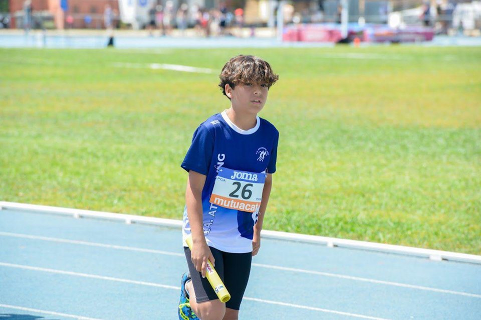 Atleta jove amb un testimoni de relleus a la mà, sobre una pista blava.
