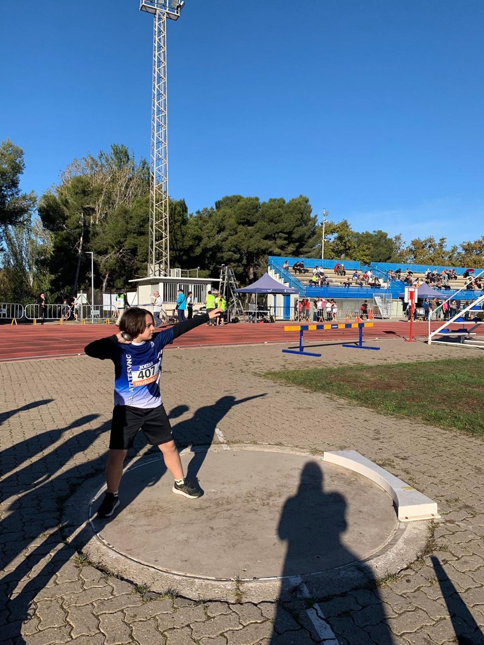 Atleta jove preparant un llançament de pes dins del cercle.